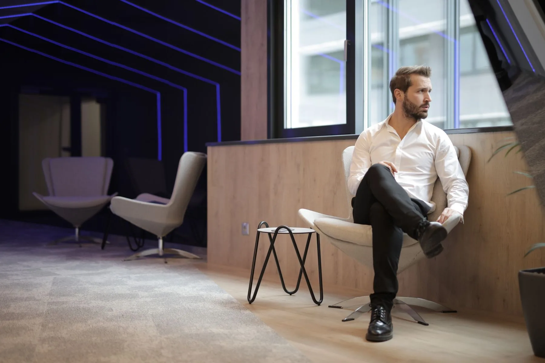 Confident executive sitting in a modern workspace near a window, gazing away in quiet thought